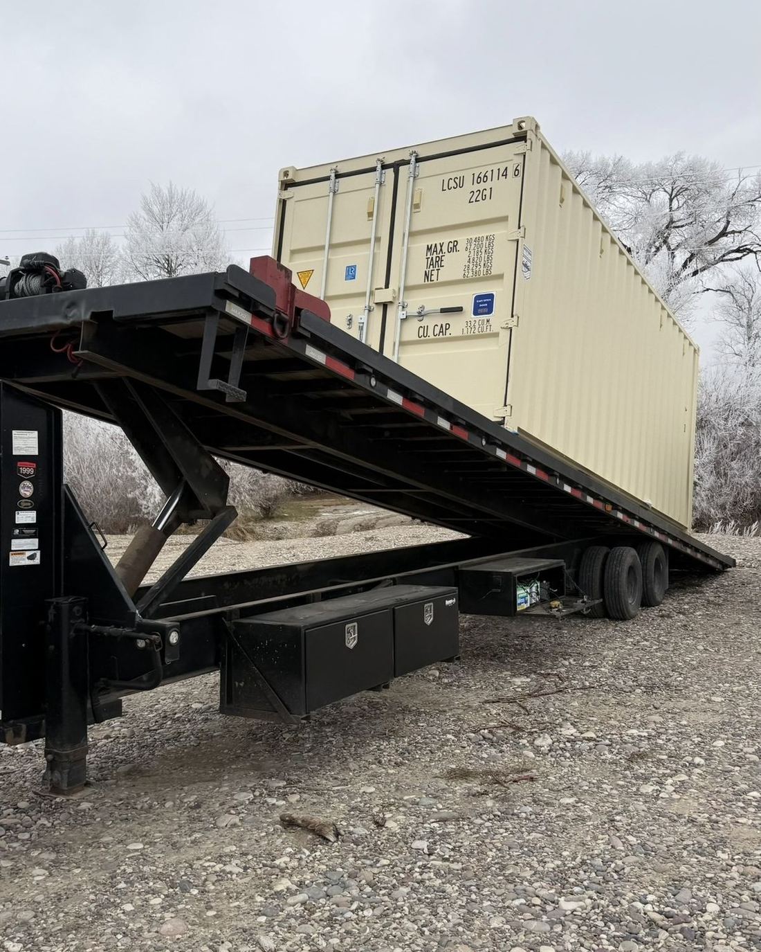 Tilt-deck trailer delivering a shipping container in winter