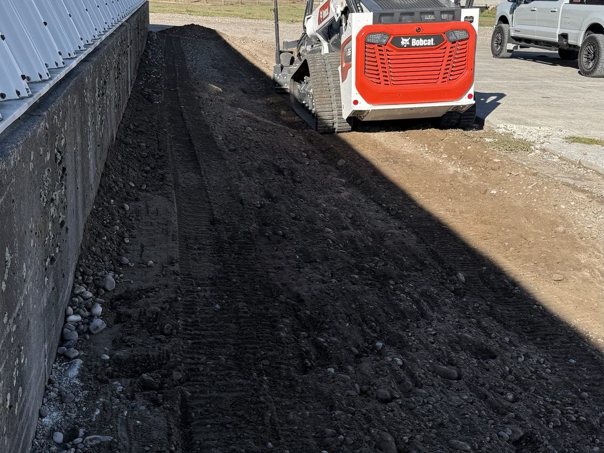 Laser-guided finish grade cut along a steel building